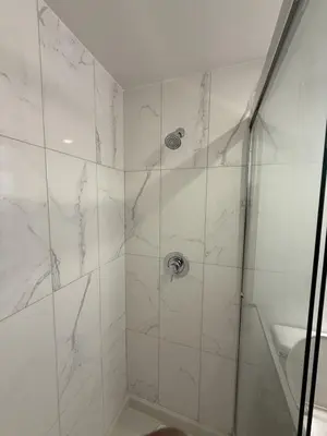a bathroom with a shower with white marble walls at Luxury Downtown One Bedroom with Skyline Views and Free Parking in Edmonton