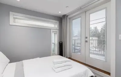 a white bedroom with a bed and a window at Large 3 Bedroom Laneway House in Vancouver
