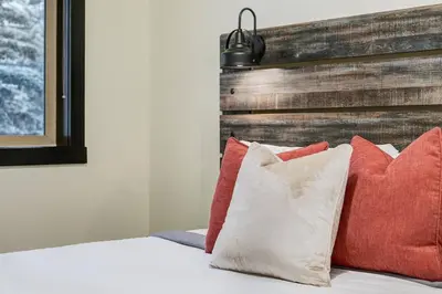a bed with four pillows and a wooden headboard at Heated Outdoor Pool Near Banff Park in Canmore