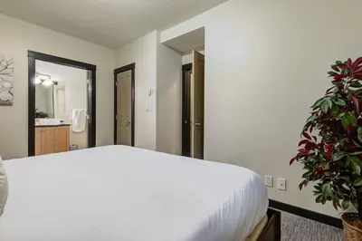 a bedroom with a white bed and a plant at Heated Outdoor Pool Near Banff Park in Canmore