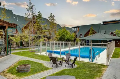 a patio with a table and chairs next to a pool at Stylish Mountain Retreat 2BR Chalet and Hot Pool in Canmore
