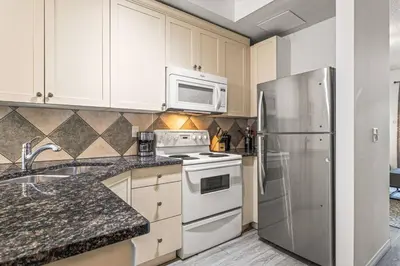 a kitchen with white cabinets and a stainless steel refrigerator at Stylish Mountain Retreat 2BR Chalet and Hot Pool in Canmore