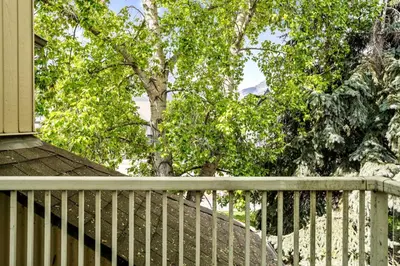 a porch with a white fence and a tree at 2BR MTN Canmore Retreat with Private Balcony in Canmore