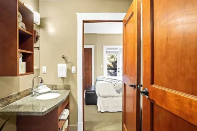 a bathroom with a sink and a room with a bed at Serene 2BR Solara Escape with BBQ Pool and Hot Tub in Canmore