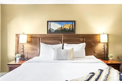 a bedroom with a large bed with two lamps at Serene 2BR Solara Escape with BBQ Pool and Hot Tub in Canmore