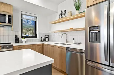a kitchen with a stainless steel refrigerator and a sink at 3BR Rockies Have Sleeps 8 with Hot Tub Pool and Mtn Views in Canmore