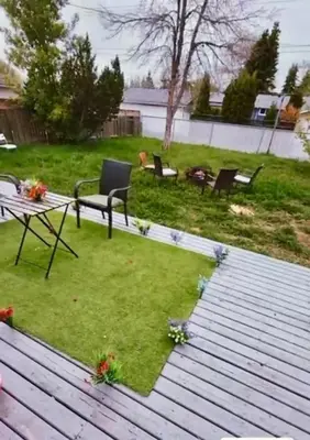 a deck with a bench and a table and grass at Beautiful Serenity in Edmonton