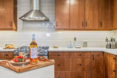 a kitchen with a bottle of wine and a bowl of fruit at Luxury 1750sf Condo In DT Canmore Sleeps 10 in Canmore