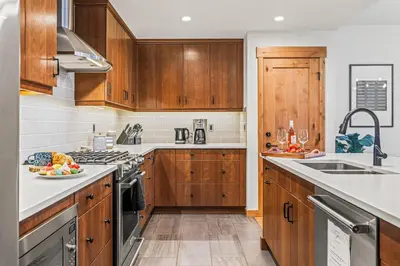 a kitchen with wooden cabinets and white counter tops at Luxury 1750sf Condo In DT Canmore Sleeps 10 in Canmore