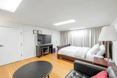 a bedroom with a bed and a couch and a tv at BudgetWise Semi-Basement near Airport, UBC, Downtown in Vancouver in Vancouver
