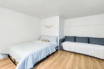 two beds in a room with white walls and wooden floors at BudgetWise Semi-Basement near Airport, UBC, Downtown in Vancouver in Vancouver