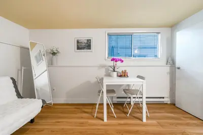 a white table and chairs in a room with a bed at BudgetWise Semi-Basement near Airport, UBC, Downtown in Vancouver in Vancouver