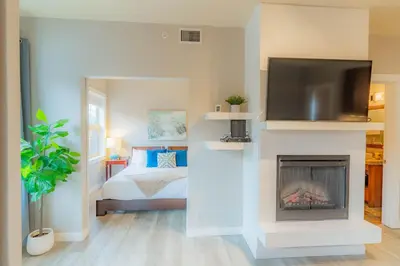 a bedroom with a bed and a tv above a fireplace at Corner Mountain View Retreat 2 Kings w Patio in Canmore