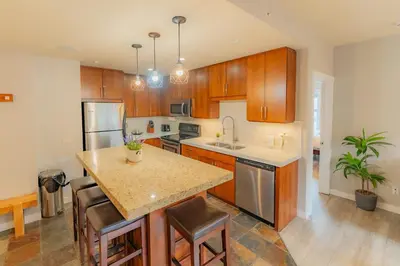 a kitchen with wooden cabinets and a island with a counter top at Corner Mountain View Retreat 2 Kings w Patio in Canmore