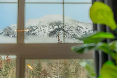 a window with a view of a snow covered mountain at Corner Mountain View Retreat 2 Kings w Patio in Canmore