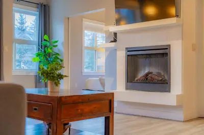 a living room with a fireplace with a table and a table sidx sidx at Corner Mountain View Retreat 2 Kings w Patio in Canmore