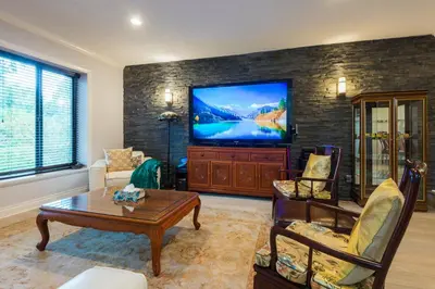 a living room with a flat screen tv on a brick wall at Luxury Home by White Rock in Surrey