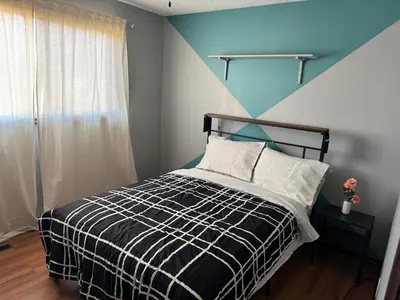 a bedroom with a black and white bed with a blue wall at All what you need in a House near GrayNuns, Millwoods in Edmonton