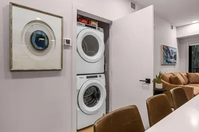 a laundry room with a washer and dryer and a couch at King Beds Fire Place New Build in Canmore