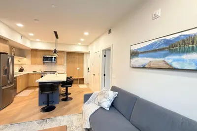 a living room with a couch and a kitchen at 3 Sisters Mountain Getaway | Luxe 2BR w Pool & Gym in Canmore