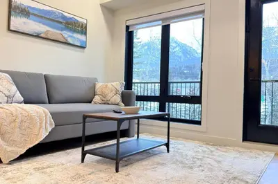 a living room with a couch and a table at 3 Sisters Mountain Getaway | Luxe 2BR w Pool & Gym in Canmore