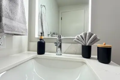 a bathroom sink with two bottles and a mirror at 3 Sisters Mountain Getaway | Luxe 2BR w Pool & Gym in Canmore