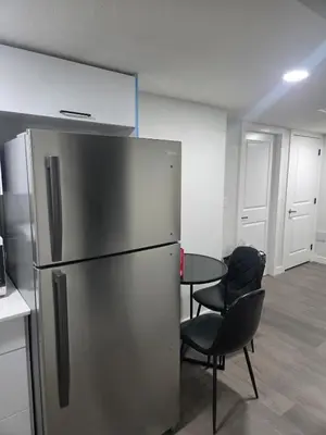 a kitchen with a refrigerator and two chairs and a table at Cozy Suite Near West Edmonton Mall in Edmonton