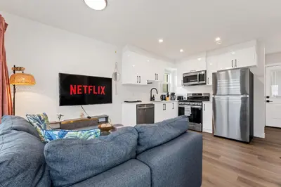 a living room with a couch and a kitchen at Modern garden suite with parking in Edmonton