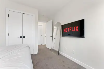 a bedroom with a bed and a tv on the wall at Modern garden suite with parking in Edmonton