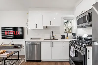 a kitchen with white cabinets and stainless steel appliances at Modern garden suite with parking in Edmonton