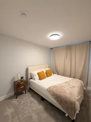 a bedroom with a bed with orange pillows and a table at Cozy and Family-friendly Newly built 3BR Home in Chestermere