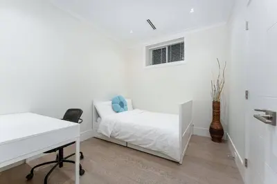 a white bedroom with a bed and a desk at New Modern 2BR Suite near UBC Pacific Spirit Park in Vancouver