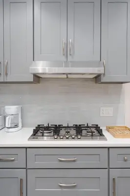 a kitchen with a stove and white cabinets at New Modern 2BR Suite near UBC Pacific Spirit Park in Vancouver