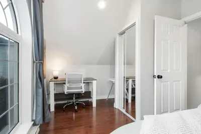 a bedroom with a desk and a chair in front of a mirror at The Loft at Marble Place a Cozy Family Retreat in Courtenay