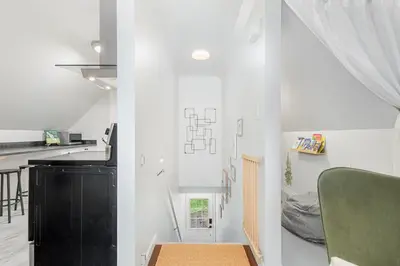 a white room with a green chair and a kitchen at The Loft at Marble Place a Cozy Family Retreat in Courtenay