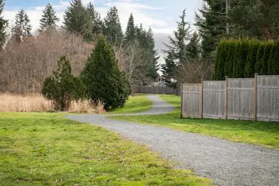 a gravel path in a yard with a fence at The Loft at Marble Place a Cozy Family Retreat in Courtenay