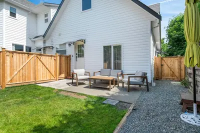 a backyard with a wooden fence and a table and chairs at The Loft at Marble Place a Cozy Family Retreat in Courtenay