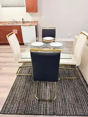 a dining room with a table and chairs on a rug at True Haven Deluxe in Prince George