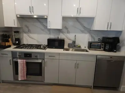 a kitchen with white cabinets and a stove and a sink at Vancouver Family Condo 2 Bedrooms 2 Baths Near UBC & Parks in Vancouver