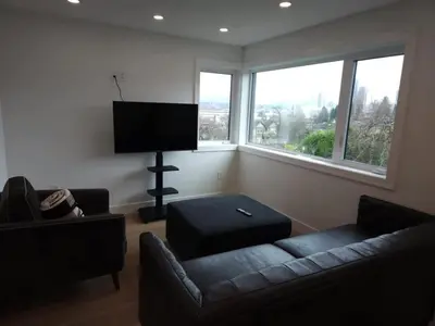 a living room with a couch and a flat screen tv at Vancouver Townhouse Family-Friendly with Street Parking & Balcony in Vancouver