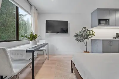 a white living room with a table and a kitchen at The Alpine Alcove w Pool & Hot Tub in Whistler