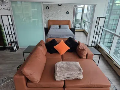a brown couch with pillows and a bed in a room at Breath-Taking-View-5 Guest DTskyline-18th Floor in Calgary