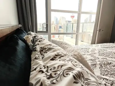 a bed with a view of a city from a window at Breath-Taking-View-5 Guest DTskyline-18th Floor in Calgary