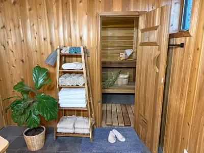 a wooden room with a towel rack and towels at Bragg Creek Vacation Estate with hot tub, sauna, pool table, karaoke, private pond and forest trails in Bragg Creek