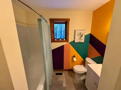 a colorful bathroom with a toilet and a shower at Bragg Creek Vacation Estate with hot tub, sauna, pool table, karaoke, private pond and forest trails in Bragg Creek