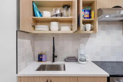 a kitchen counter with a sink and cups and plates at NEW Cambie Village 2 Bed Suite Near Skytrain in Vancouver