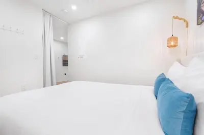 a white room with a bed and a blue couch at NEW Cambie Village 2 Bed Suite Near Skytrain in Vancouver