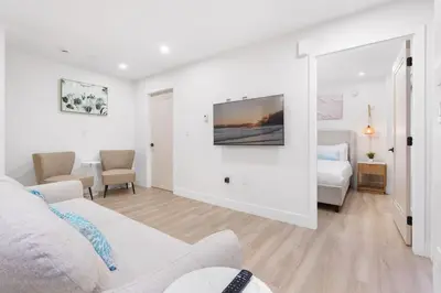 a white living room with a bed and a tv at NEW Cambie Village 2 Bed Suite Near Skytrain in Vancouver