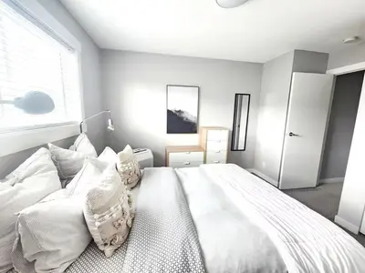 a white bedroom with a large white bed with pillows at Modern Lake City Getaway in Penticton