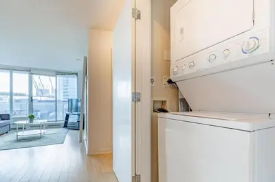 a kitchen with a stove top oven next to a living room at Downtown Suite with Parking, Pool, Gym in Vancouver